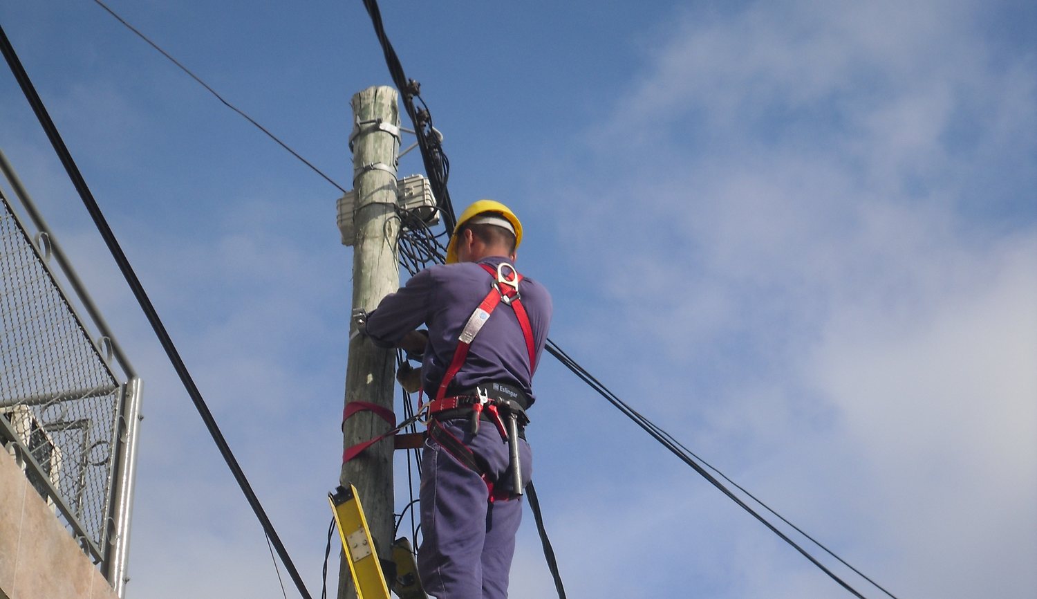 Cuadrilla de planta externa tendiendo fibra óptica sobre poste